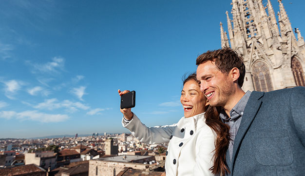 Young expat couple taking a selfie on a phone camera outside popular tourist spot