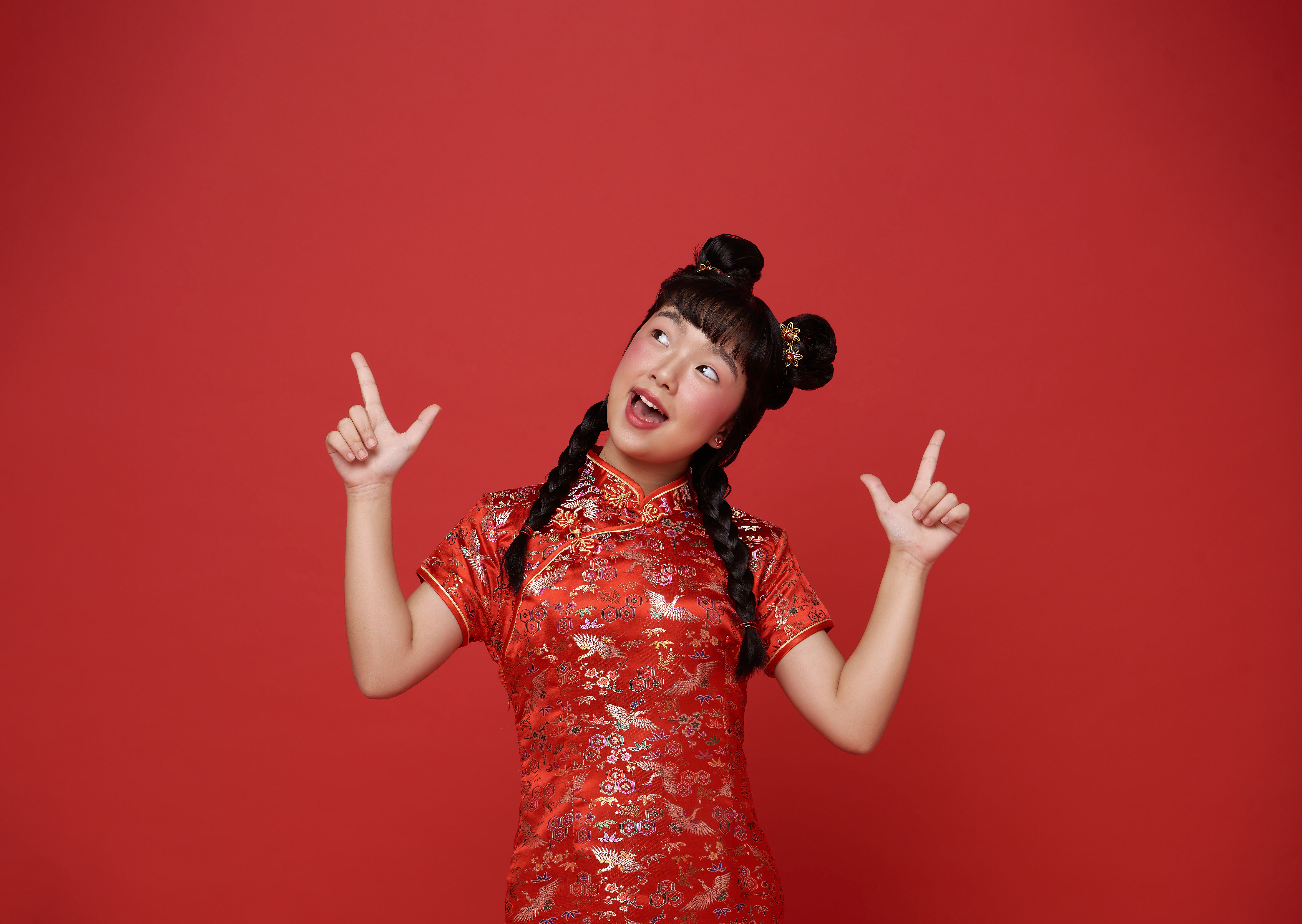 Chinese girl wearing a red, traditional Chinese qipao, standing in front of a red background.