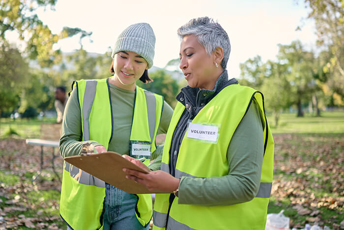 two people in high-vis with volunteer name badges looking at a clipboard
