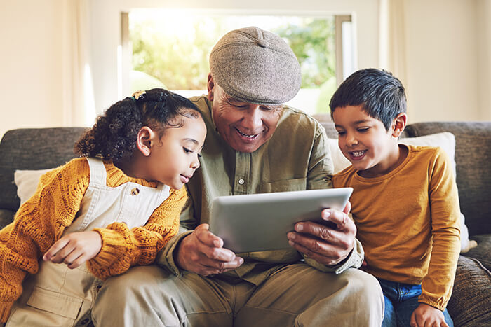 man is laughing at a tablet with two children on either side