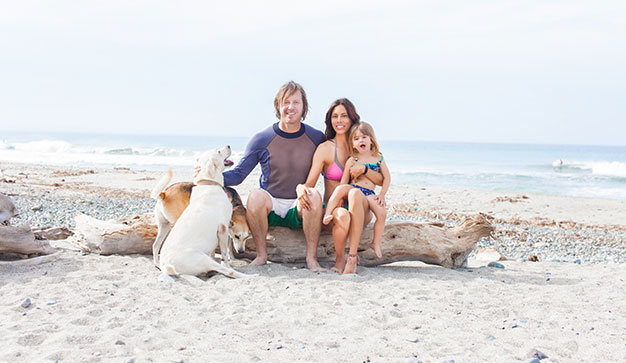 Expat Family on a beach with dogs smiling at camera