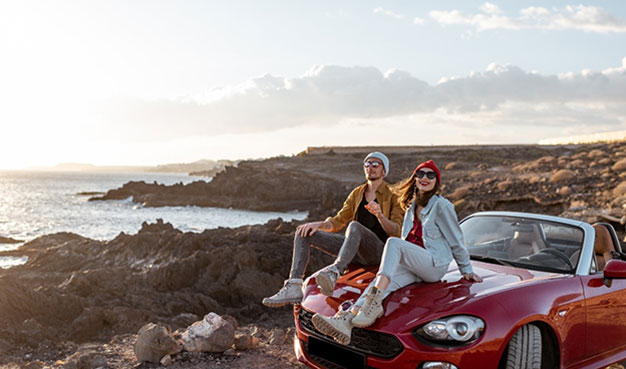 Expats sat on car near a beach enjoying life