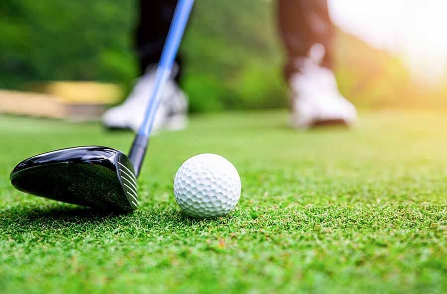 Close up of a ball and driver while golfer lines up shot