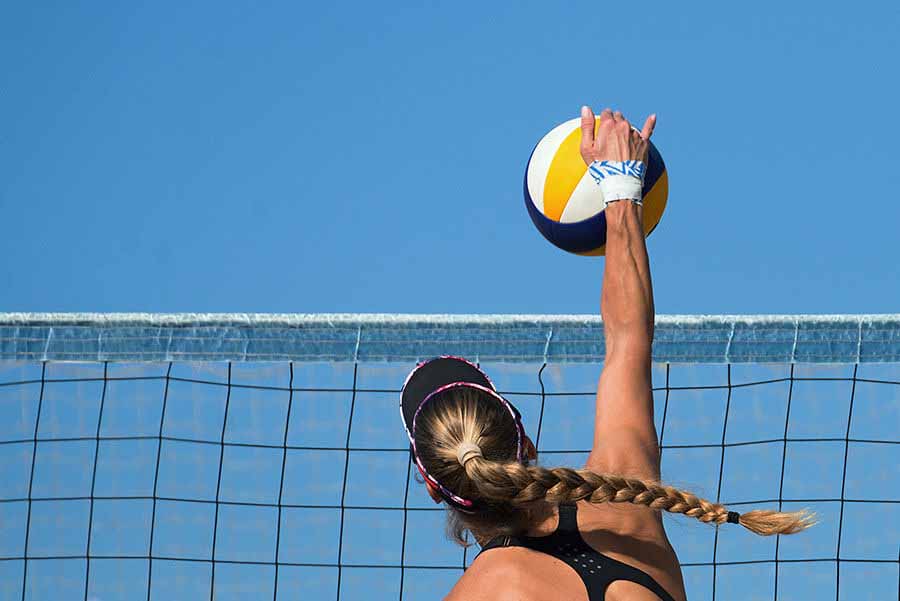 Woman reaching over a volleyball net to hit the ball