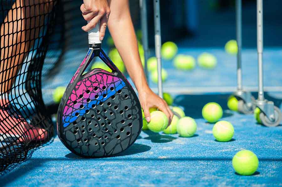 Player holding Padel racket while picking up balls