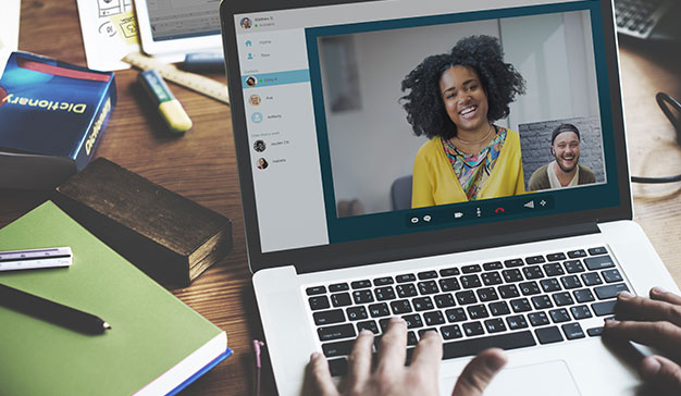 Man sat on laptop video calling home friend to help with homesickness