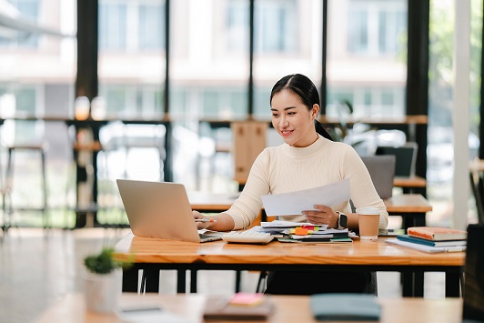 asian woman sitting in cafe and looking at laptop