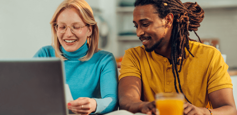 couple smiling and looking at a laptop