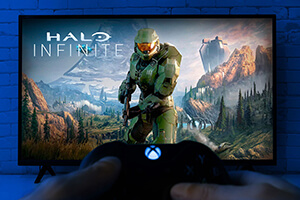 Halo Infinite load screen with a hand holding an X-box controller in foreground