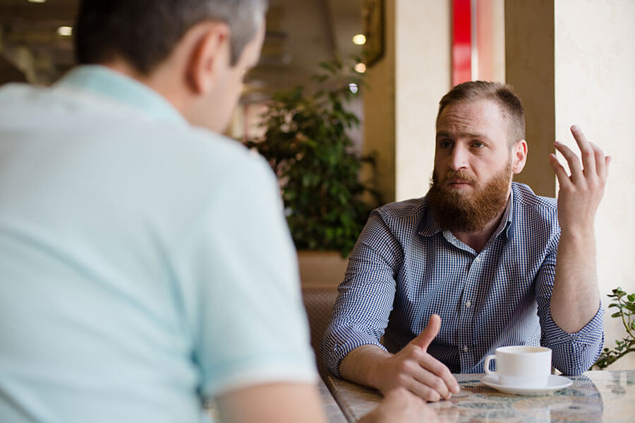 Two men having a serious discussion over a cup of coffee