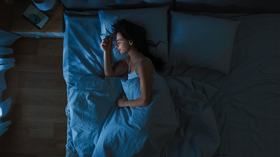 Woman smiling as she sleeps in a big bed