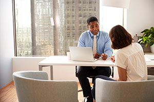 A male financial adviser sat behind his desk offering advice to a woman