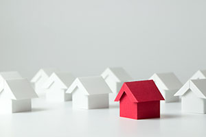 A red cardboard house surrounded by white cardboard houses