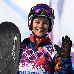 Zoe Gillings-Brier holding a snowboard and waving at camera