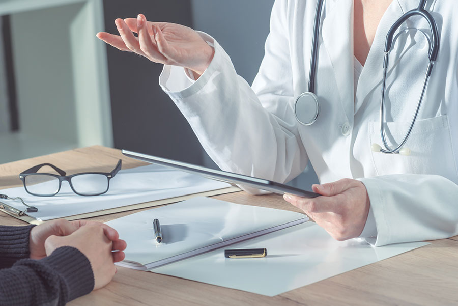 Doctor reading a tablet and talking to a patient