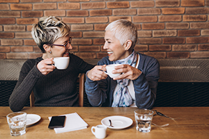 Women drinking coffee laughing and smiling