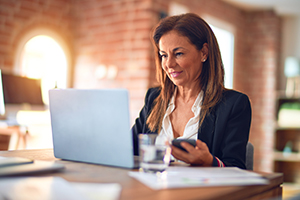 Working woman sat at desk on laptop in business attire