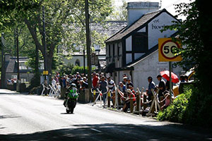 Road-side spectators watching a motorbike drive past outside the Hawthorn