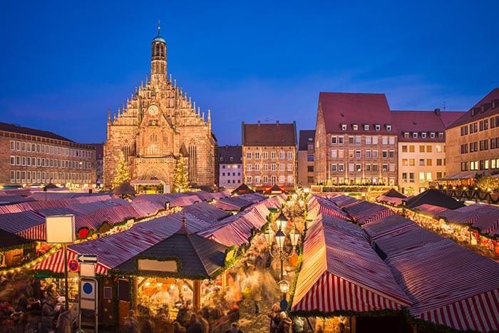 a market with many stalls all with red and whte striped roofs and yellow lights. its very quaint.