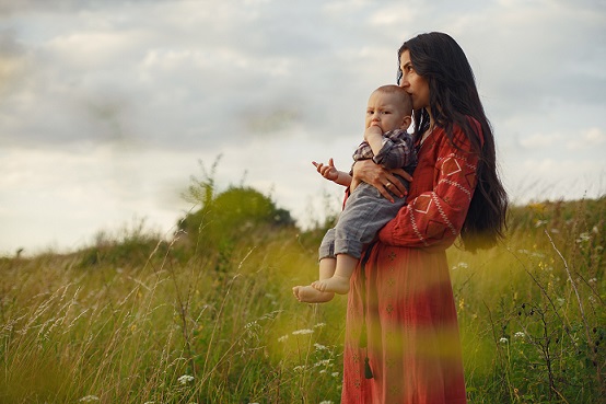 side view of a woman holding baby in a field